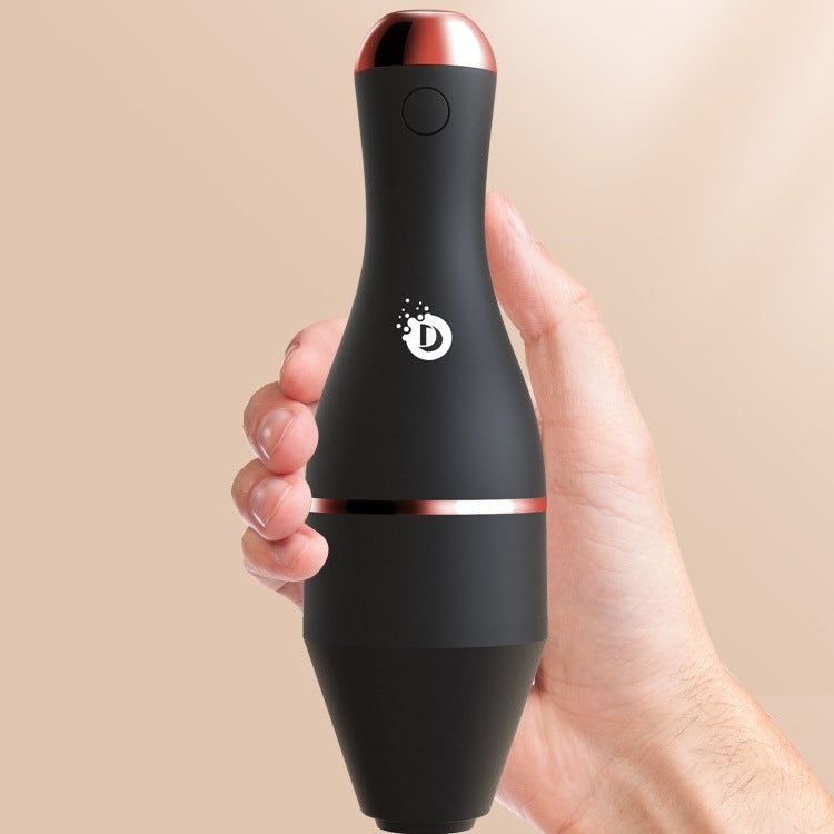 Hand holding a matte black, bowling-pin shaped electric makeup brush cleaner with rose gold accents and logo.