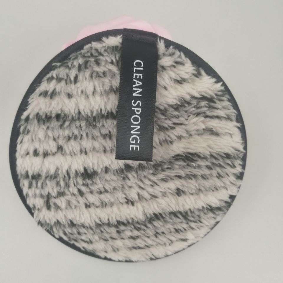 Round, fuzzy, black and white microfiber makeup remover sponge with a "CLEAN SPONGE" label on a light background.