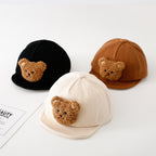 Three baby hats in black, tan, and cream corduroy, each featuring a cute fuzzy brown teddy bear face on the front.
