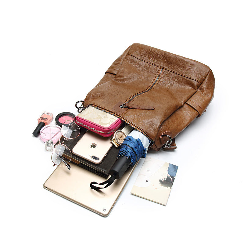 Brown soft leather backpack by Digitaldistribution375, filled with a tablet, wallet, umbrella, and accessories.