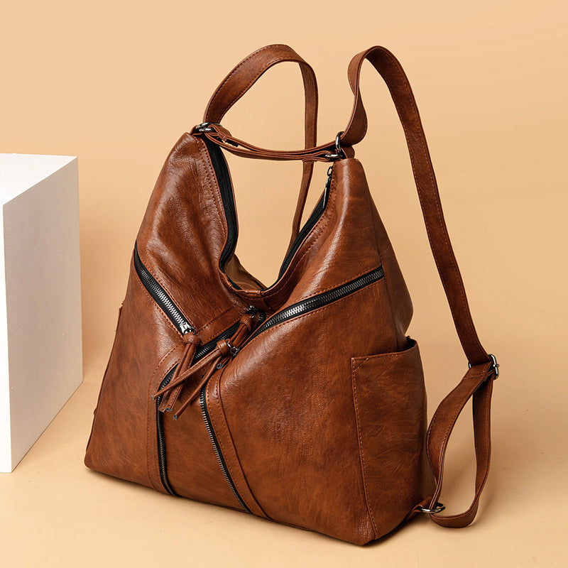 Brown leather convertible shoulder bag and backpack with decorative front zipper accents and slim, adjustable straps.