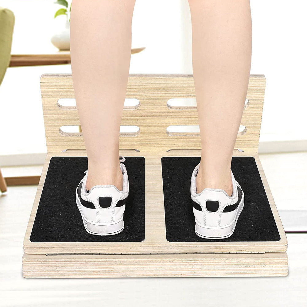 Person standing on a light wood adjustable slant board with black non-slip grip pads for home fitness training.