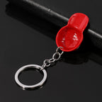 Shiny red enamel baseball cap charm on a silver-tone metal chain and keyring, set against a black background.