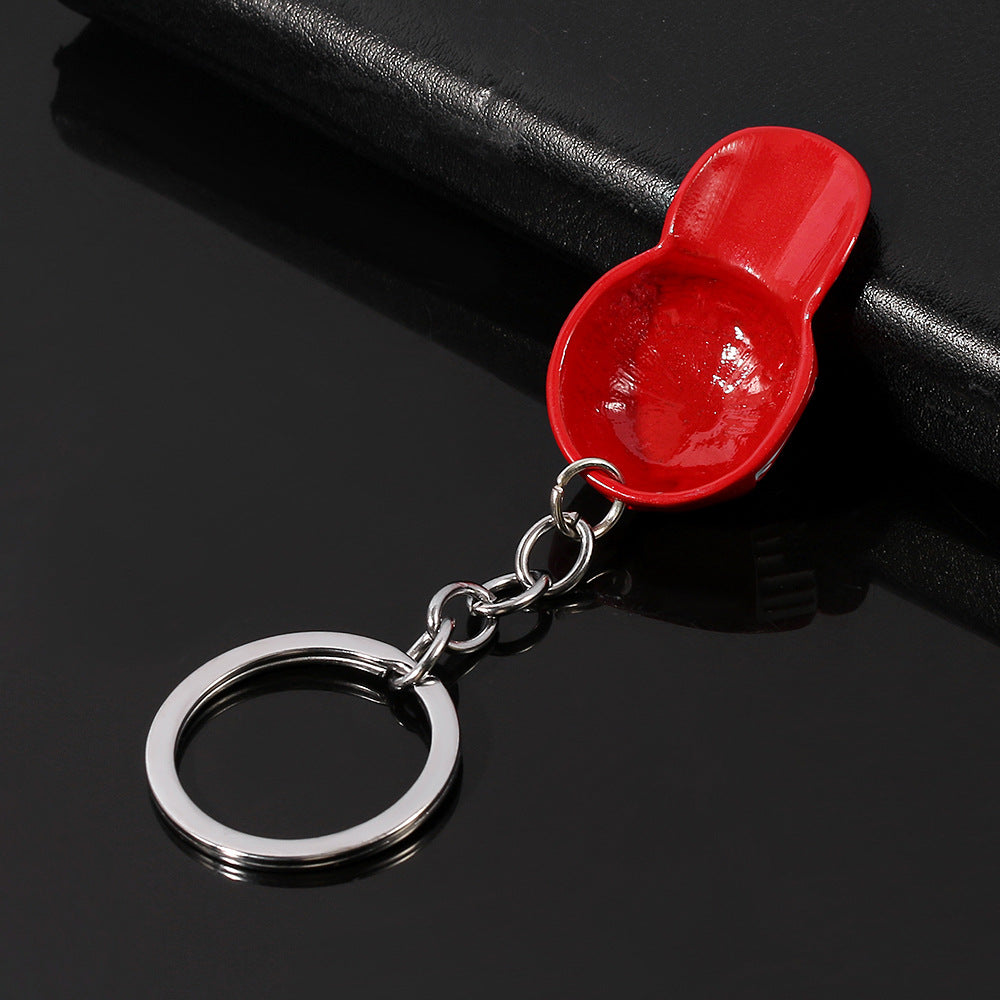 Shiny red enamel baseball cap charm on a silver-tone metal chain and keyring, set against a black background.