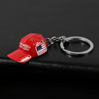 Red metal baseball cap keychain featuring "MAKE AMERICA GREAT AGAIN" and a small flag design with a silver ring.
