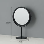 A round, black metal tabletop makeup mirror with a swivel design, measuring 28cm tall and 19cm wide.