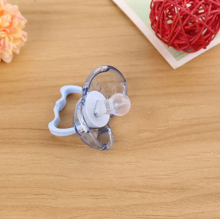 Clear plastic baby pacifier with a light blue handle, featuring a round silicone nipple on a wooden table background.