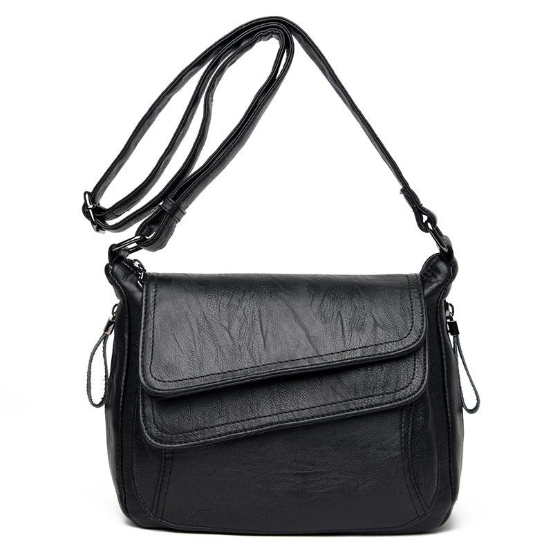 Black soft leather crossbody bag with an adjustable shoulder strap and a multi-layered, fold-over flap design.