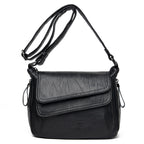 Black soft leather crossbody bag with an adjustable shoulder strap and a multi-layered, fold-over flap design.