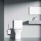 White toilet brush set with a slim handle and wall-mounted base in a modern, minimalist bathroom setting.