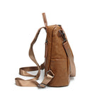 Side view of a brown soft leather convertible backpack with adjustable nylon straps and metal hardware on white.