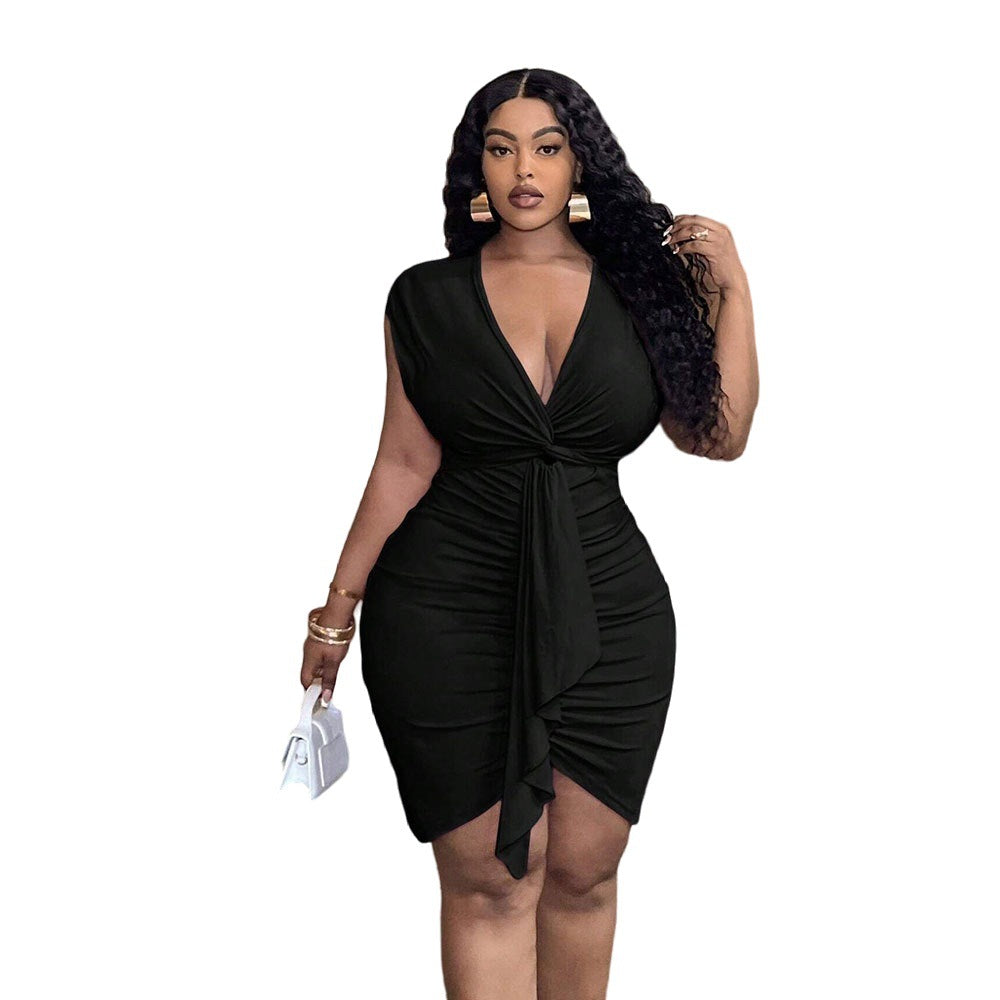A woman wears a black, V-neck, sleeveless, waist-cinched dress with a ruffled front detail and hip-hugging fit.