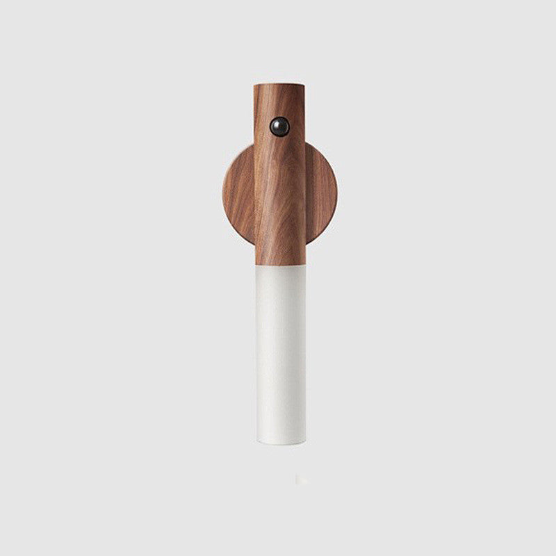 Minimalist wooden wall light with motion sensor and cylindrical frosted LED shade against a white background.