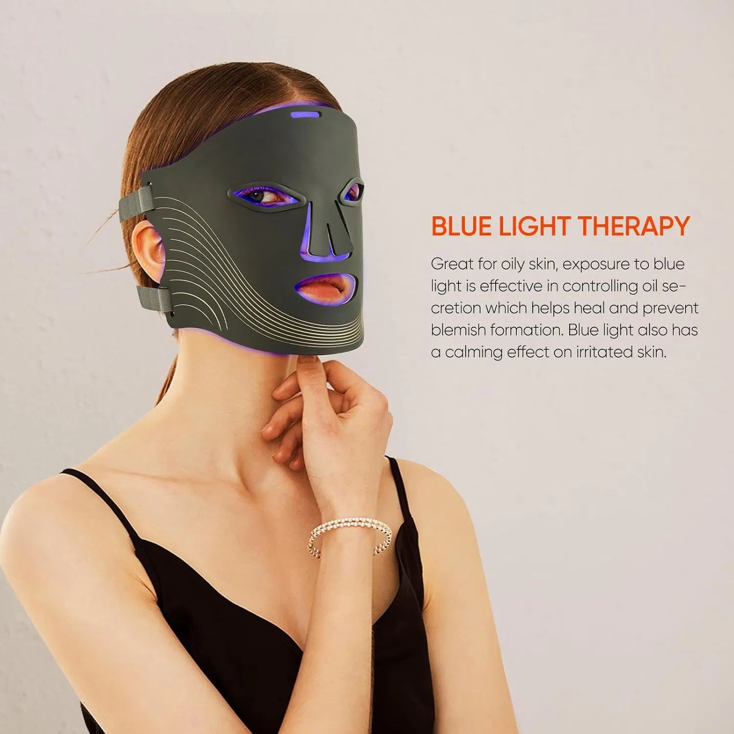 A person wearing a black cordless 7-color LED face mask emitting blue light for acne and wrinkle reduction treatment.