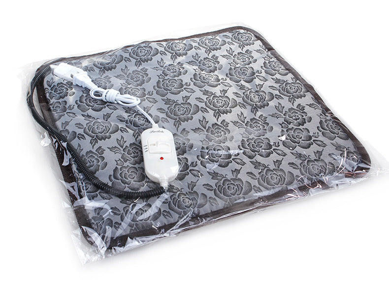 Square grey floral pet heating pad in plastic packaging with a white wired temperature controller and protective cord.