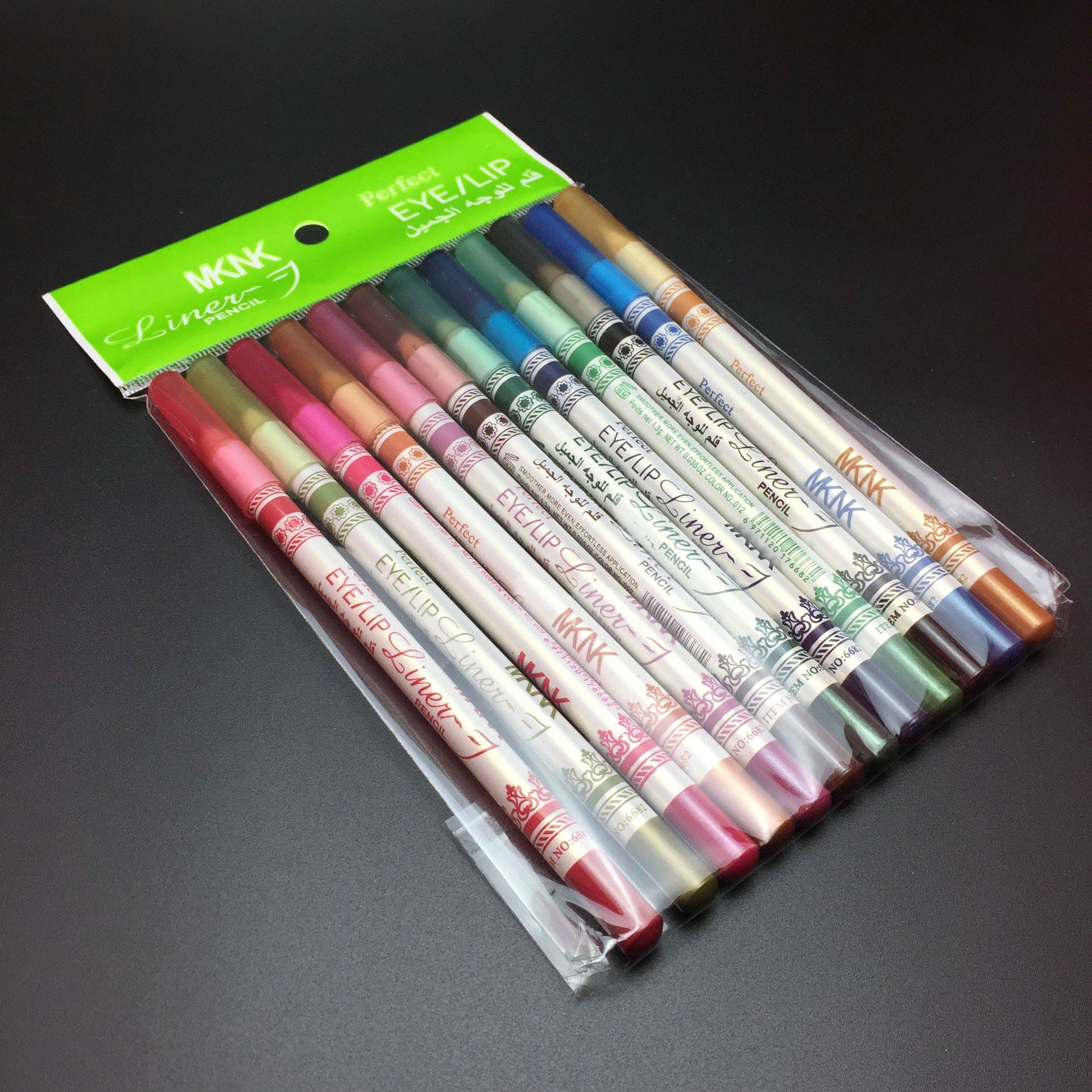 Twelve MKNK glitter eye and lip liner pencils in assorted colors, packaged in a clear plastic sleeve.