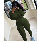 Woman wearing a dark olive green, ribbed long-sleeve crop top and matching high-waisted leggings leisure set.