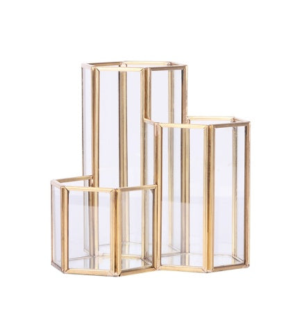 Hexagonal makeup brush holder with tiered clear glass panels and a gold metal frame.