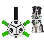 Black and white paw-print soccer ball toy with green nylon grab tabs, held by a Border Collie.