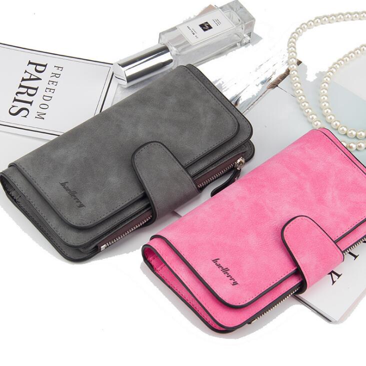 Grey and pink faux suede bi-fold wallets with snap closures and zipper detailing, displayed on a flat lay.