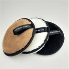 Three round, fuzzy, brown, white, and black cleansing makeup remover pads with black "CLEAN SPONGE" ribbon loops.