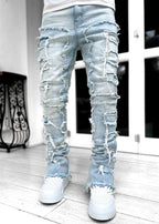 Light blue, stacked, distressed denim jeans featuring raw-edge patches, ripped details, and a tight, fitted cut.