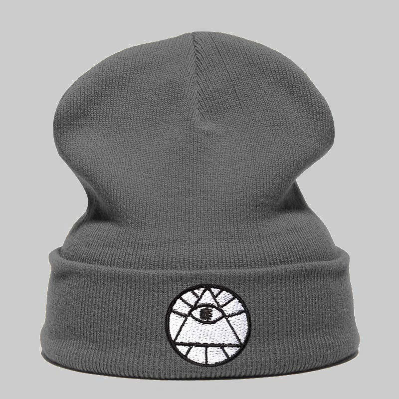 Charcoal gray knit beanie featuring a white embroidered circular patch with an all-seeing eye design.