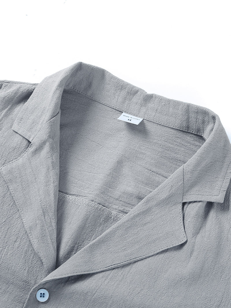 Close-up of a grey short-sleeve button-down shirt with a notched collar, featuring a textured linen-like fabric.