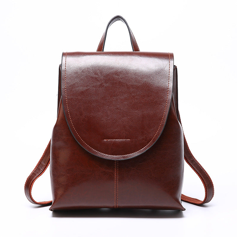 A polished brown leather retro-style women's backpack with a top handle, flap closure, and adjustable shoulder straps.