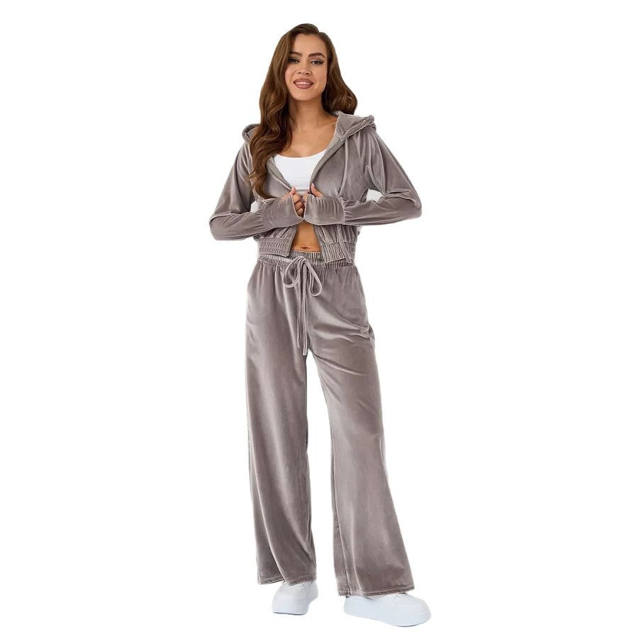 A woman wearing a gray velour zip-up hoodie and matching wide-leg drawstring trousers over a white top.