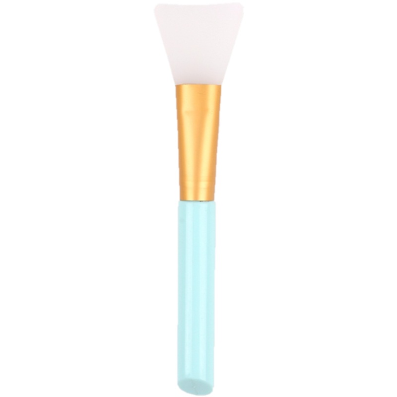 White silicone face mask brush with gold ferrule and light blue handle against a white background.