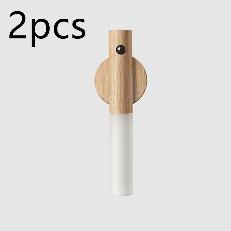 Two light-wood, motion-sensor LED wall lamps with white cylindrical shades. Minimalist magnetic design.