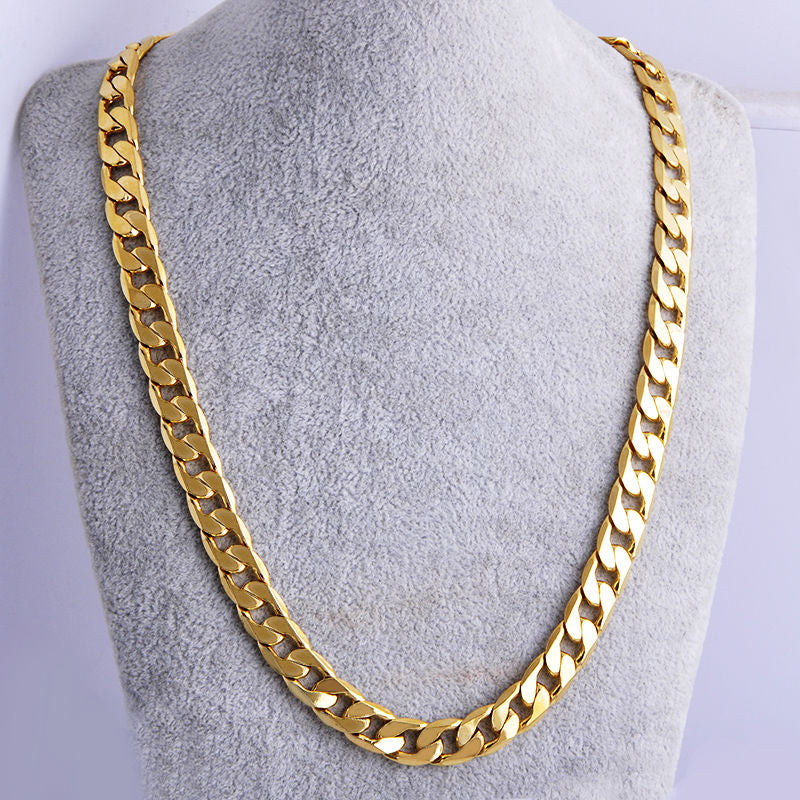 Thick, polished gold-tone hip hop cuban link chain necklace displayed on a grey velvet jewelry bust.