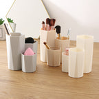 Grey and beige hexagonal plastic makeup brush holders on a wooden desk, holding brushes and sponges.