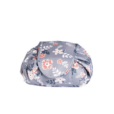 Grey fabric cosmetic bag with a peach floral print, featuring a drawstring closure and a fold-over flap.