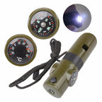 Olive green 7-in-1 survival whistle with compass, thermometer, and LED light on a black lanyard against white background.