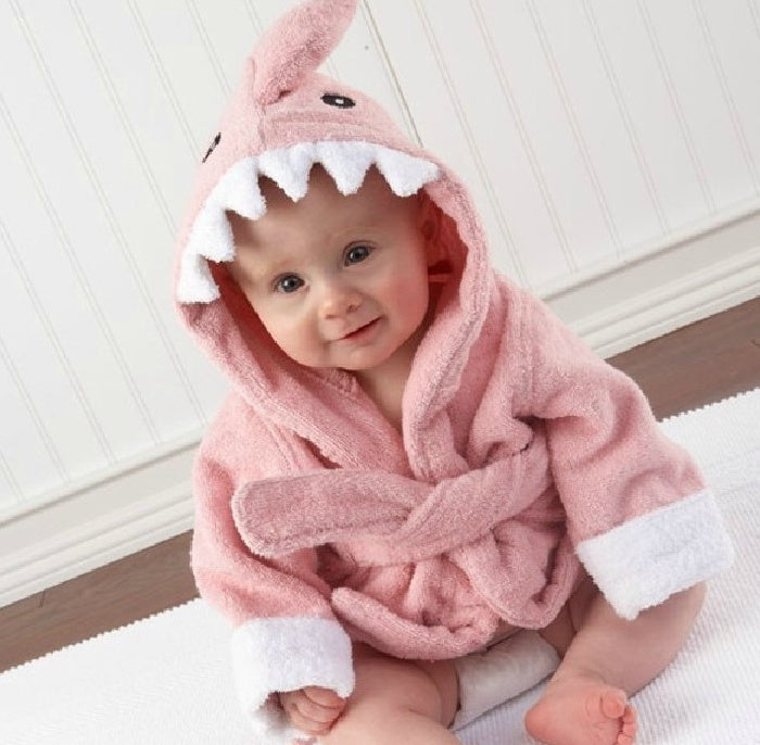 Baby in a soft, pink cotton hooded bathrobe featuring a playful shark design with white teeth and a dorsal fin.