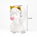 White resin girl bust vase, featuring a gold cat-ear headband and a pink bubble gum sphere. 16.2cm tall.