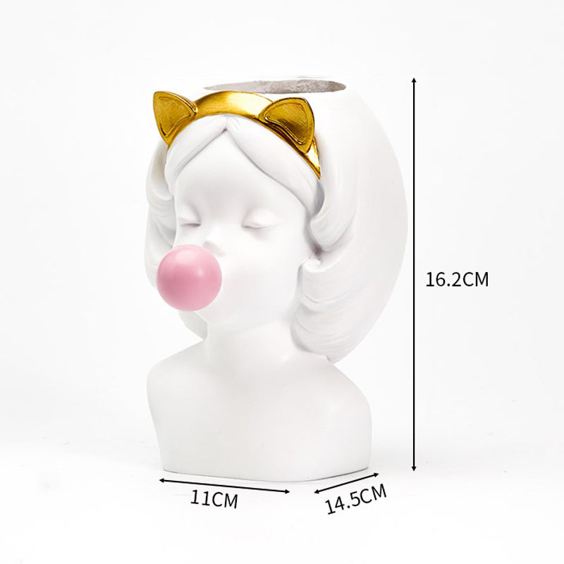 White resin girl bust vase, featuring a gold cat-ear headband and a pink bubble gum sphere. 16.2cm tall.