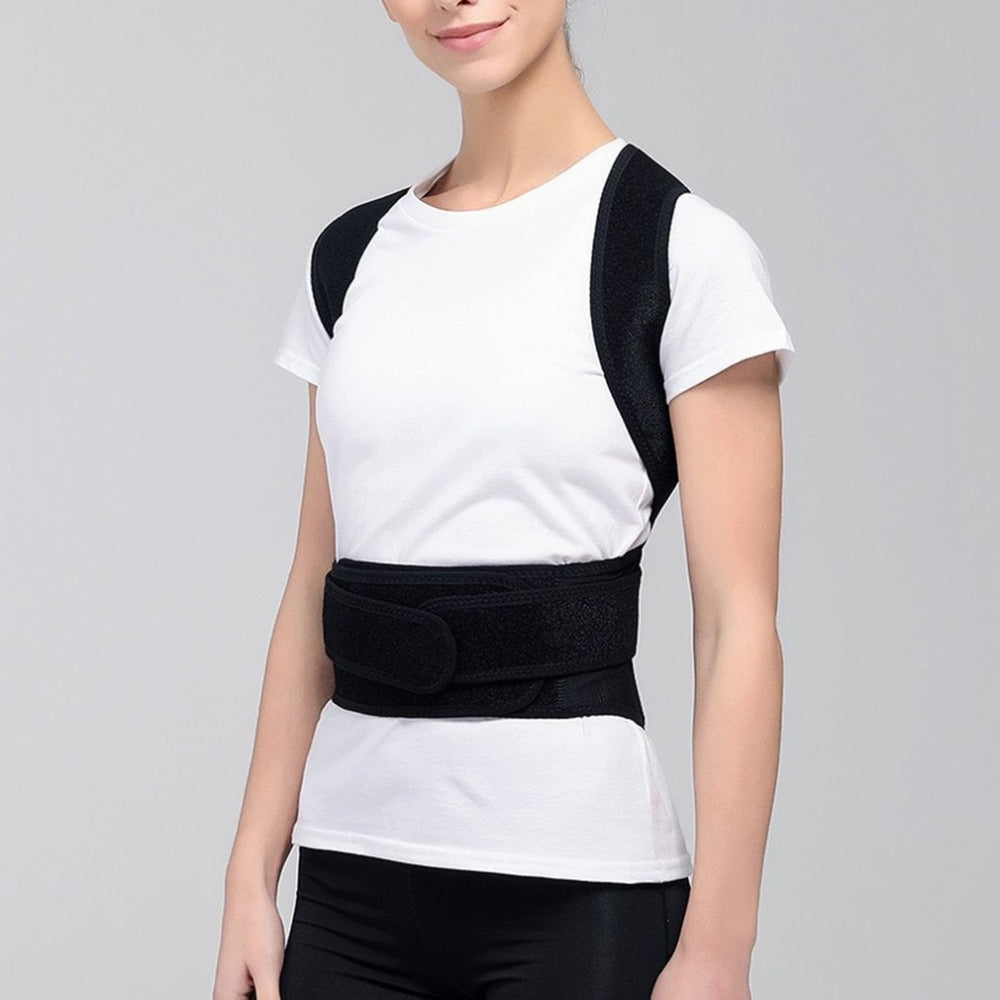 A person wearing a black, adjustable fabric posture corrector over a white t-shirt, featuring shoulder and waist straps.