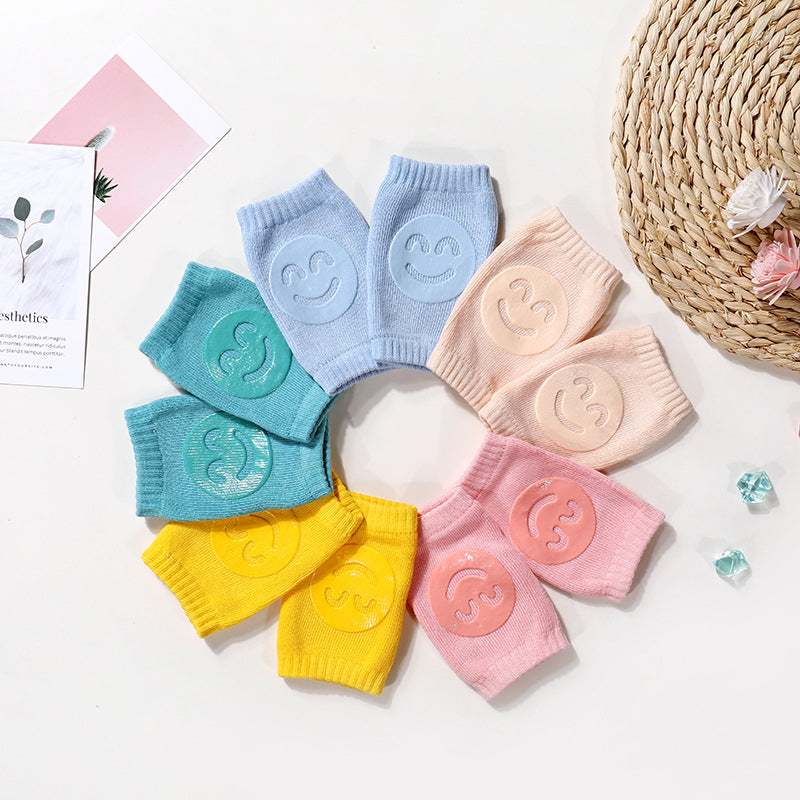 Circular arrangement of colorful terry cloth baby knee pads, each featuring a raised silicone smiley face.