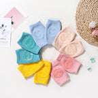 Circular arrangement of colorful terry cloth baby knee pads, each featuring a raised silicone smiley face.