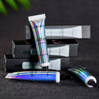 Holographic Handaiyan glitter primer tubes stacked against black boxes on a dark surface.