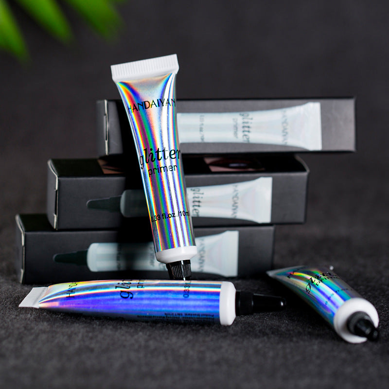 Holographic Handaiyan glitter primer tubes stacked against black boxes on a dark surface.