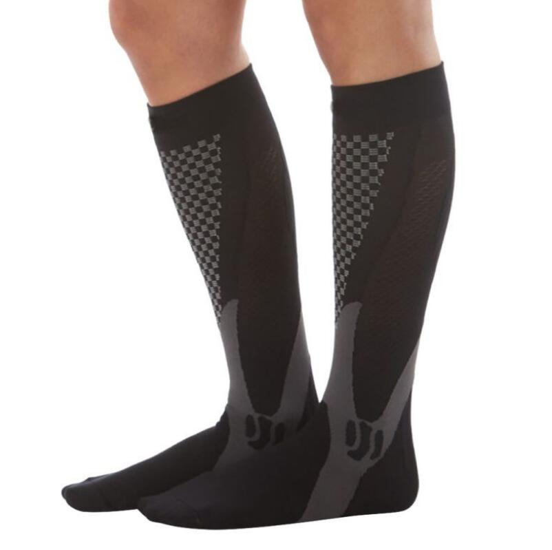 Black compression socks with grey checkered pattern and ergonomic arch support on person’s lower legs.