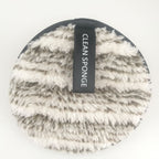Round, fuzzy, beige and brown makeup remover pad with a black "CLEAN SPONGE" label on a white background.