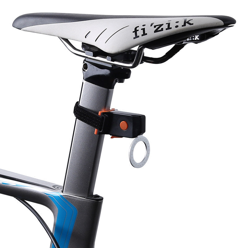 Black and orange USB bicycle taillight strapped to a bike seat post, featuring a circular light ring.