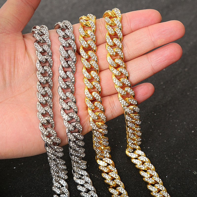 Four gold and silver-toned chunky cuban link bracelets paved with sparkling crystals held in a hand.