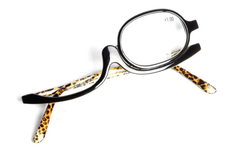 Black makeup reading glasses with a single flip lens and leopard print temples on a white background.