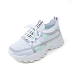 White lace-up sneakers in breathable mesh with light green and grey accents on a chunky white rubber sole.